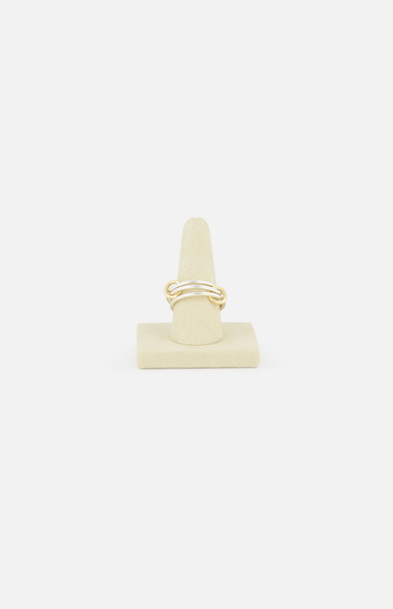The Solarium SG 3 Band Ring by SPINELLI KILCOLLIN, a minimalist gold twisted band, is displayed on a beige cone-shaped ring holder against a plain white background.