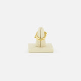 The SPINELLI KILCOLLIN Jovie Double Pave Ring, featuring an intertwined modular design, is showcased upright on a beige fabric-covered holder set against a plain white background.
