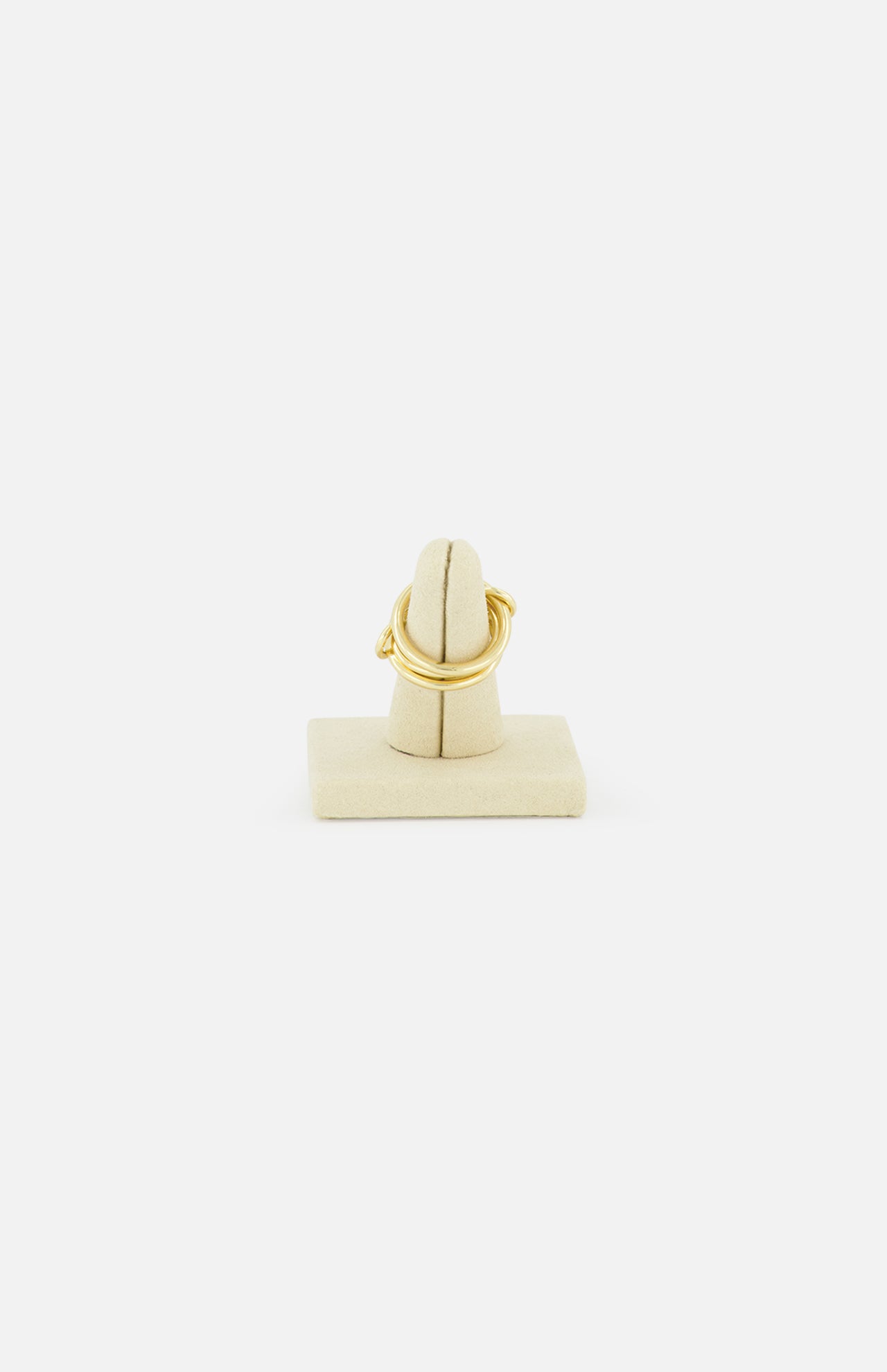 The SPINELLI KILCOLLIN Jovie Double Pave Ring, featuring an intertwined modular design, is showcased upright on a beige fabric-covered holder set against a plain white background.