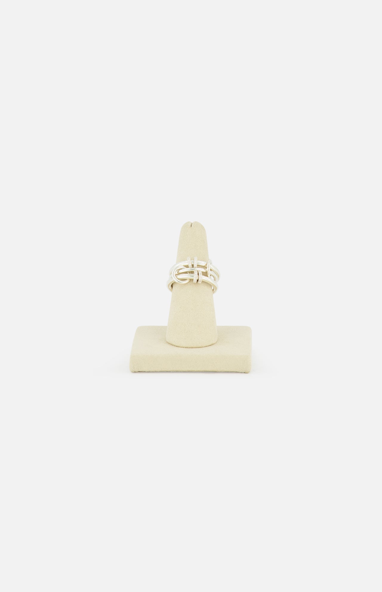 The SPINELLI KILCOLLIN Jovie Double Pave Ring, featuring an abstract intertwined sterling silver design, is displayed on a beige ring stand against a plain white background.