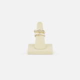 The SPINELLI KILCOLLIN Nimbus 4 Band Diamond Ring features a bold, knot-inspired design with sparkling diamonds, shown upright on a beige ring holder against a white background.