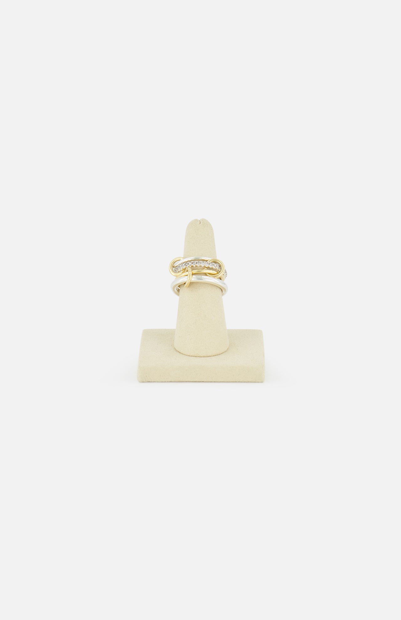 The SPINELLI KILCOLLIN Nimbus 4 Band Diamond Ring features a bold, knot-inspired design with sparkling diamonds, shown upright on a beige ring holder against a white background.