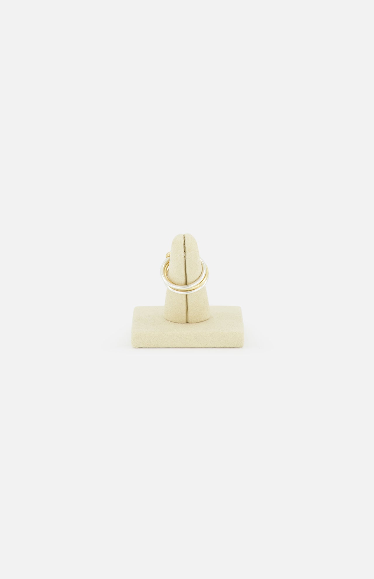 A SPINELLI KILCOLLIN Solarium 3 Band Ring, crafted from sterling silver and yellow gold, is displayed upright on a beige stand against a plain white background.