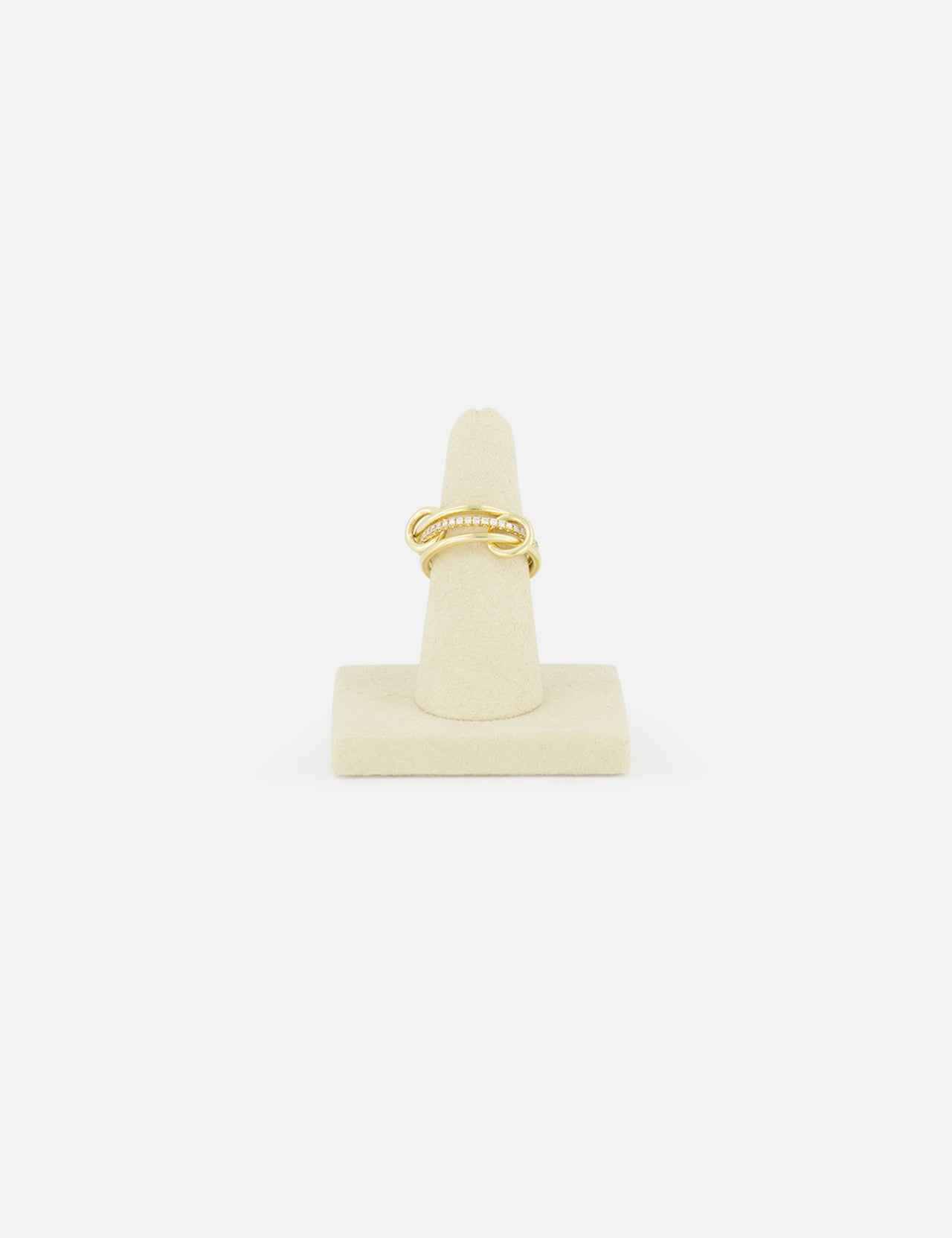 The SPINELLI KILCOLLIN Sonny Pavé Band Ring in yellow gold, featuring a twisted design with pavé diamonds, is displayed upright on a beige ring holder against a plain white background.