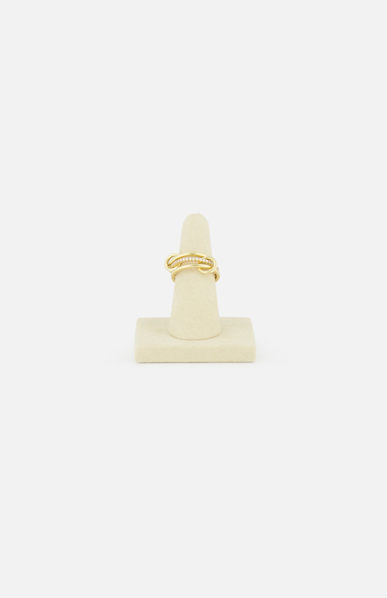 The SPINELLI KILCOLLIN Sonny Pavé Band Ring in yellow gold, featuring a twisted design with pavé diamonds, is displayed upright on a beige ring holder against a plain white background.
