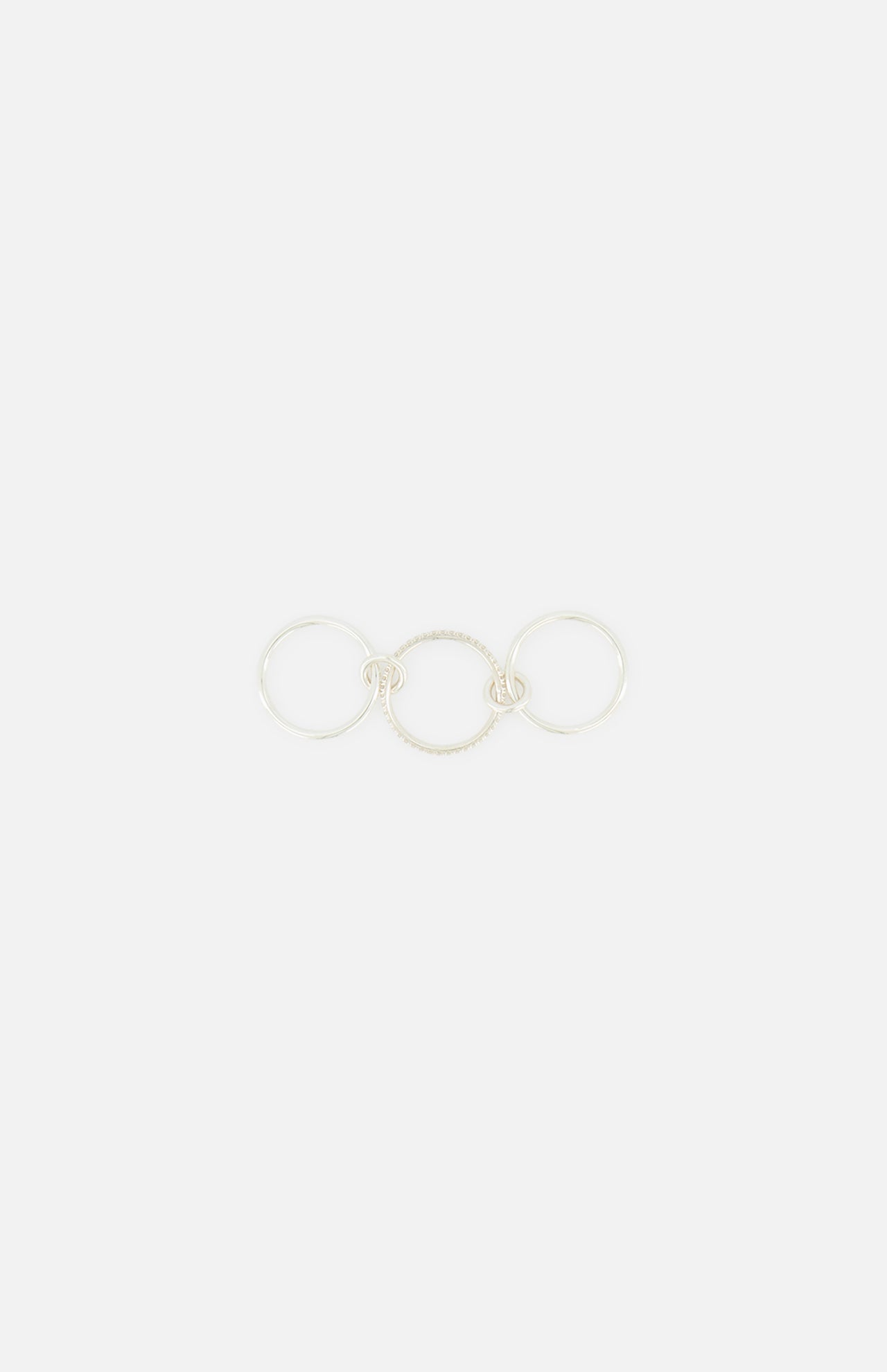 The SPINELLI KILCOLLIN Sonny Pavé Band Ring is a sterling silver piece with three connected circles, featuring a pavé diamond-encrusted center band, shown on a plain white background.