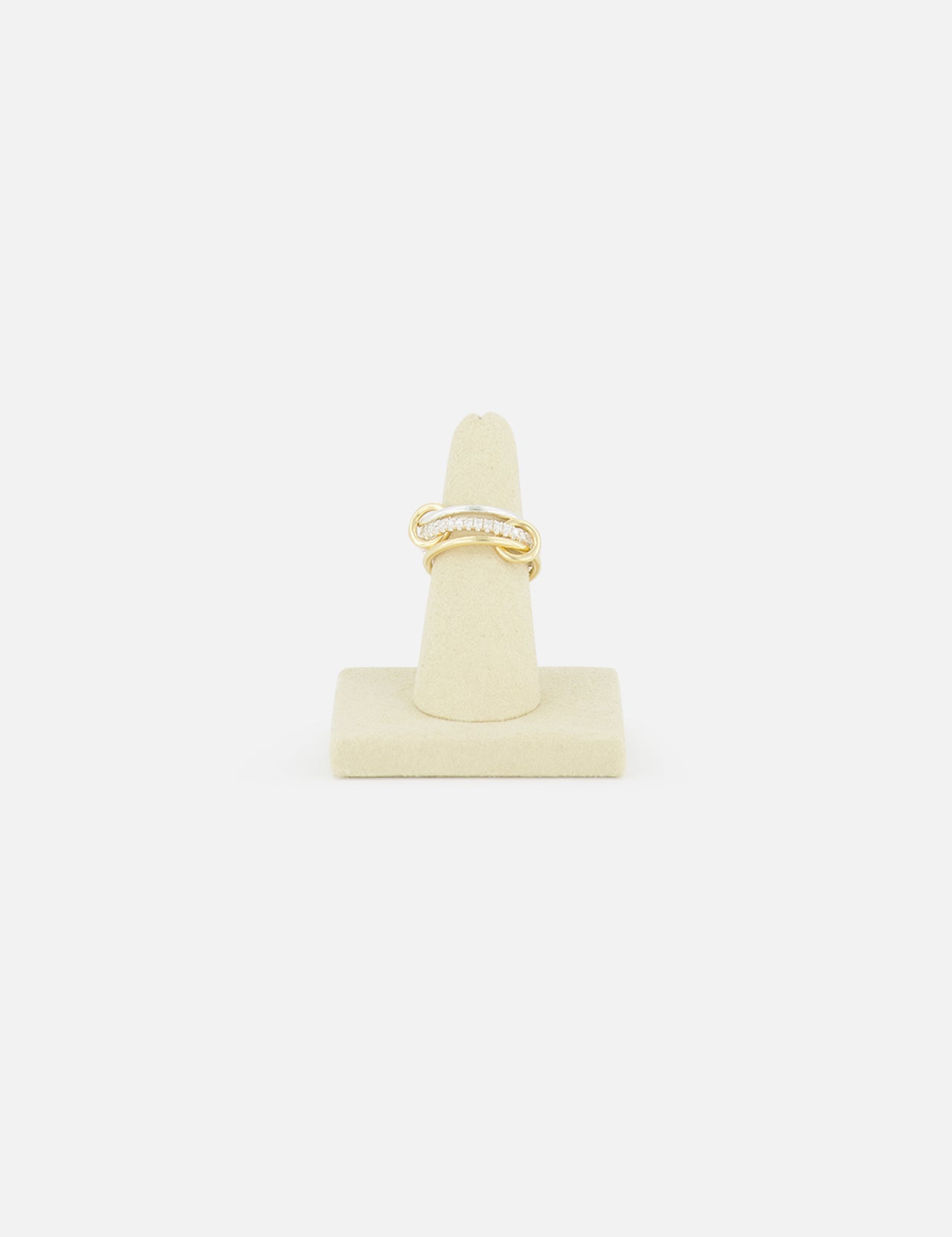 The SPINELLI KILCOLLIN Tigris Pavé Band Ring, featuring a twisted gold design with small pavé diamonds, is displayed upright on a beige stand against a white background, highlighting its modular elegance.