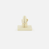 The SPINELLI KILCOLLIN Tigris Pavé Band Ring, featuring a curved gold design with pavé-set white stones, is displayed on a beige velvet ring stand against a plain white background, highlighting its modular jewelry artistry.