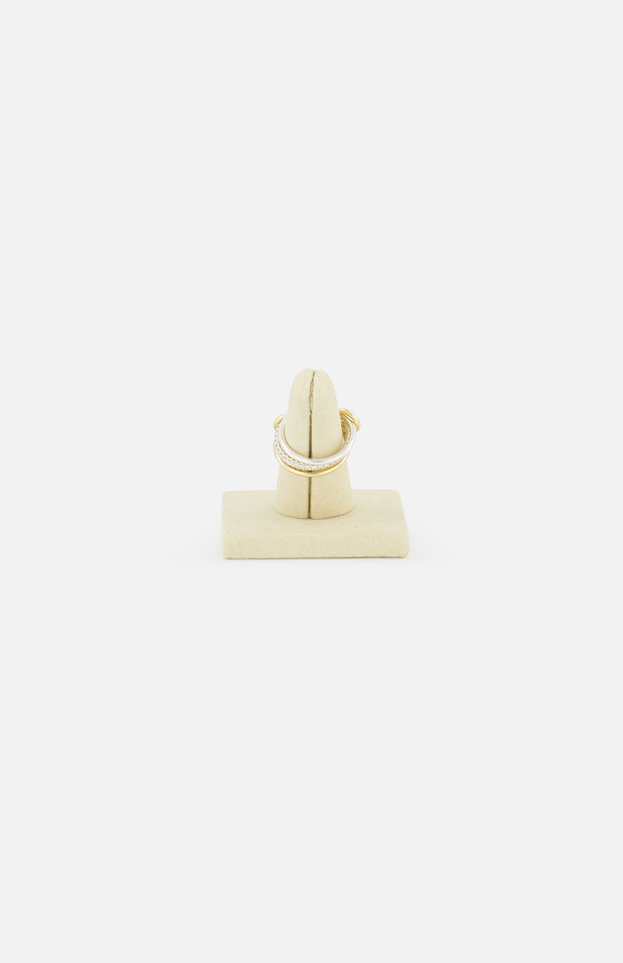 The SPINELLI KILCOLLIN Tigris Pavé Band Ring, featuring a curved gold design with pavé-set white stones, is displayed on a beige velvet ring stand against a plain white background, highlighting its modular jewelry artistry.