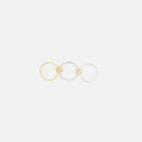 SPINELLI KILCOLLIN’s Tigris Pavé Band Ring is shown alongside gold and silver rings, each with a small knot detail, reflecting the brand’s modular jewelry style. The pavé ring is accented with clear stones.