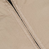 Close-up of the STONE ISLAND Hooded Full Zip Drawcord Jacket in beige, showcasing a vertical black zipper and detailed stitching inspired by innovative Japanese fabric—ideal for streetwear fans.