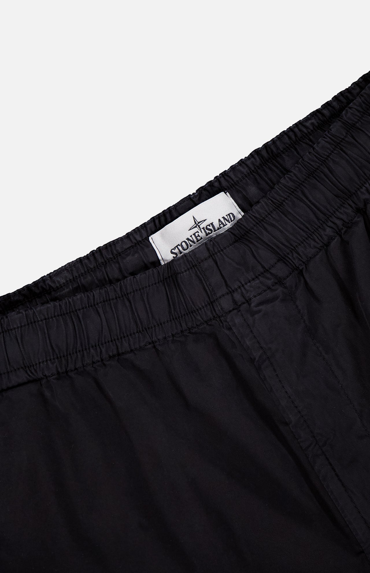 Close-up of the waistband on STONE ISLAND Drawstring Cargo Trouser Pant, featuring an elastic band and a white inside label with the brand’s logo—an essential streetwear detail.