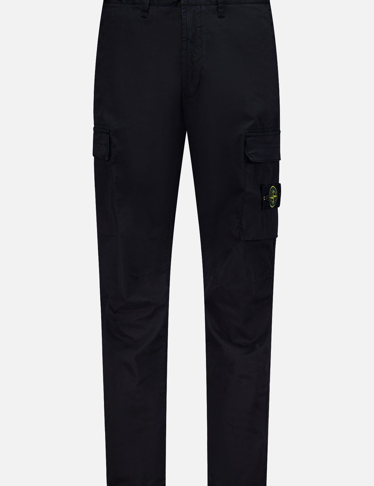 STONE ISLAND Cotton Stretch Cargo Trouser Pants in black, featuring side pockets and a button closure. A yellow and green circular Stone Island logo patch accents one pocket. These streetwear-inspired cargo pants are showcased against a plain white background.