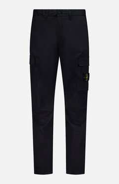 STONE ISLAND Cotton Stretch Cargo Trouser Pants in black, featuring side pockets and a button closure. A yellow and green circular Stone Island logo patch accents one pocket. These streetwear-inspired cargo pants are showcased against a plain white background.
