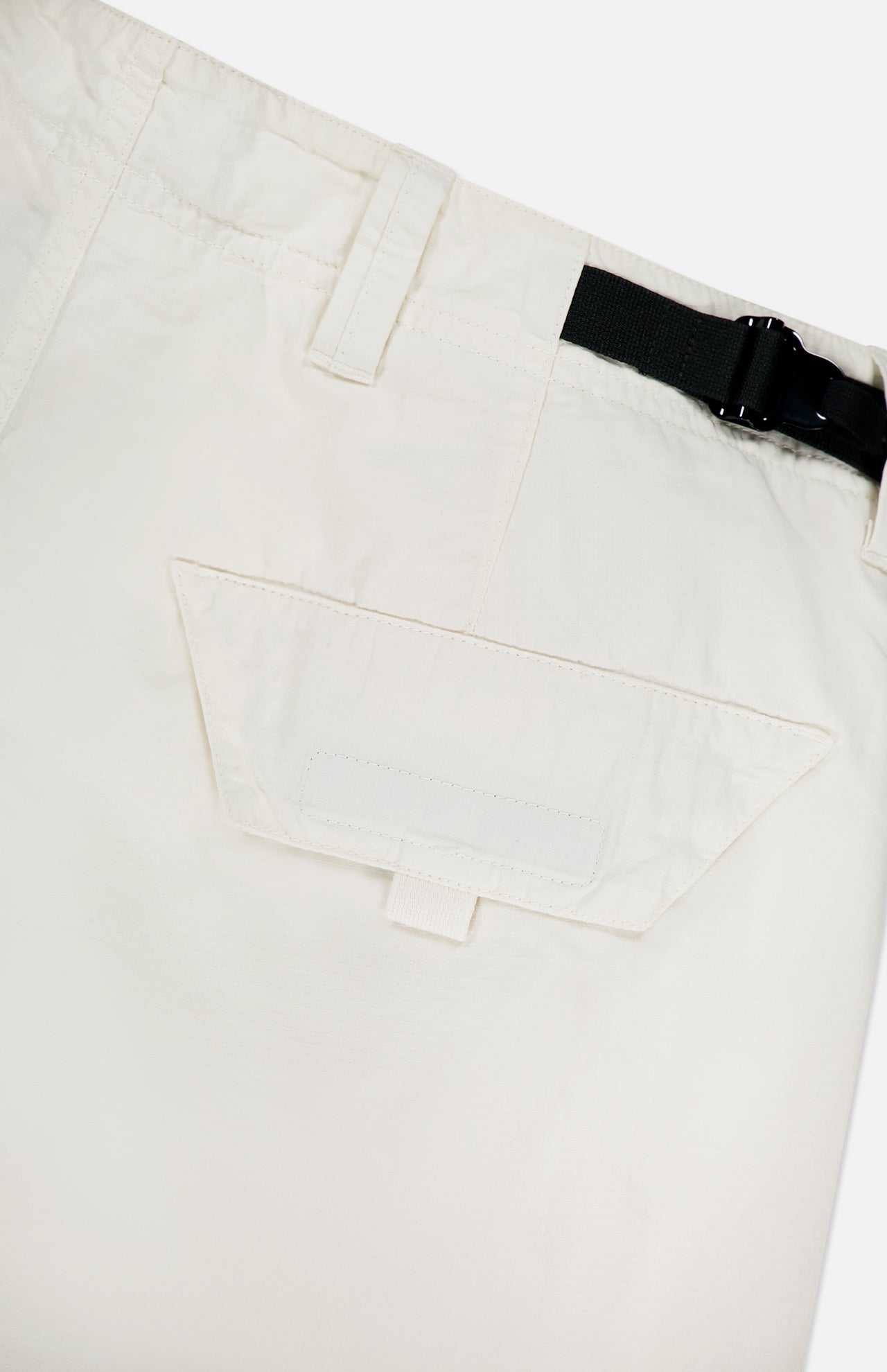 Close-up of STONE ISLAND Cargo Trousers in off-white, showcasing a flap pocket with Velcro closure and a partially visible black belt with plastic buckle at the waistband for a modern sportswear touch.