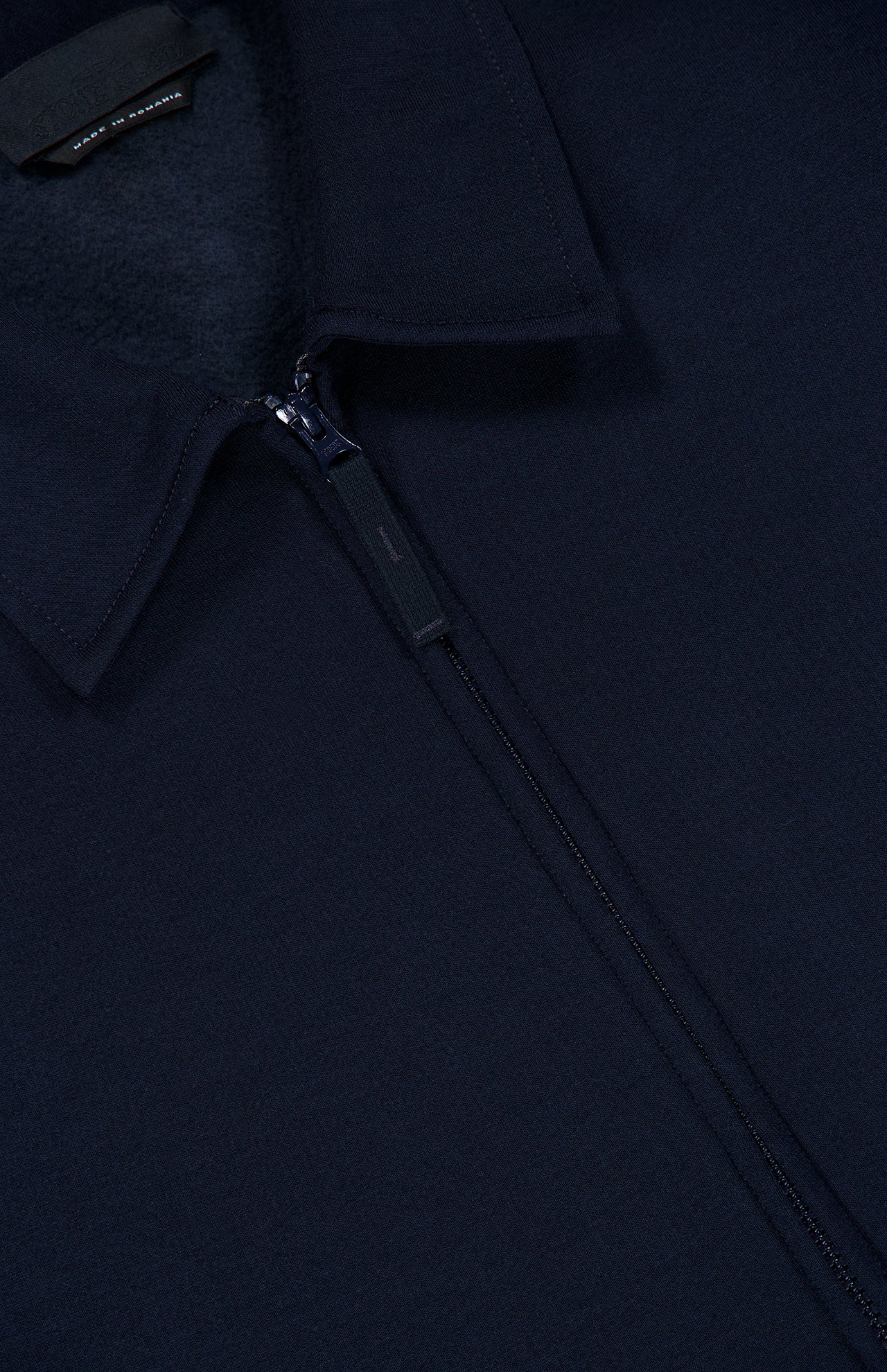 Close-up of the Coach Full Zip Jacket by STONE ISLAND in navy blue, highlighting the collar, zipper, and part of the fleece inner lining. This wool-cotton jacket features a small black tag with visible text near the collar.