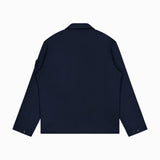 A STONE ISLAND Coach Full Zip Jacket in navy blue is shown from the back, featuring a straight hem, collar, buttoned cuffs, and a small pocket on the upper left sleeve. The wool-cotton jacket stands out elegantly against the plain white background.