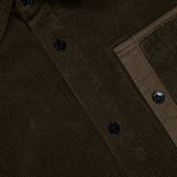 Close-up of the STONE ISLAND Corduroy Chest Pocket Overshirt in dark brown, highlighting black buttons, visible collar, chest pocket detail, and textured fabric inspired by classic men's sportswear.