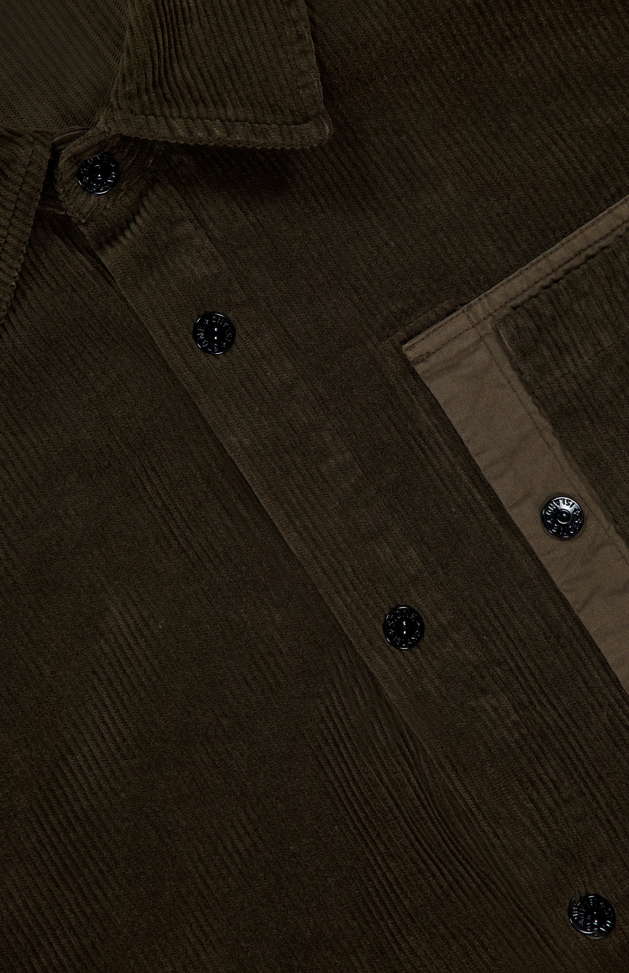 Close-up of the STONE ISLAND Corduroy Chest Pocket Overshirt in dark brown, highlighting black buttons, visible collar, chest pocket detail, and textured fabric inspired by classic men's sportswear.