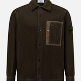 The STONE ISLAND Corduroy Chest Pocket Overshirt in brown features a front chest pocket, collar, and the iconic black patch with yellow and green compass logo on the left sleeve—an essential men's sportswear piece.