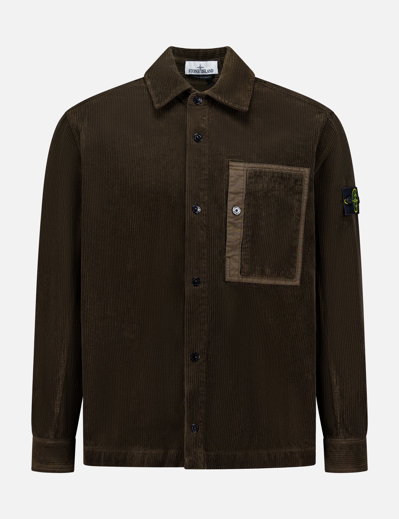 The STONE ISLAND Corduroy Chest Pocket Overshirt in brown features a front chest pocket, collar, and the iconic black patch with yellow and green compass logo on the left sleeve—an essential men's sportswear piece.