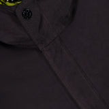 Close-up of a dark textured STONE ISLAND Double Layer Long Parka Coat with a black button, showing a yellow-green inner lining and the STONE ISLAND label near the collar.