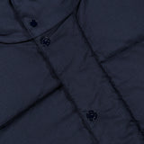 Close-up of a dark navy Stone Island Ghost Hooded Puffer Jacket featuring a detachable hood and a snap-button placket.