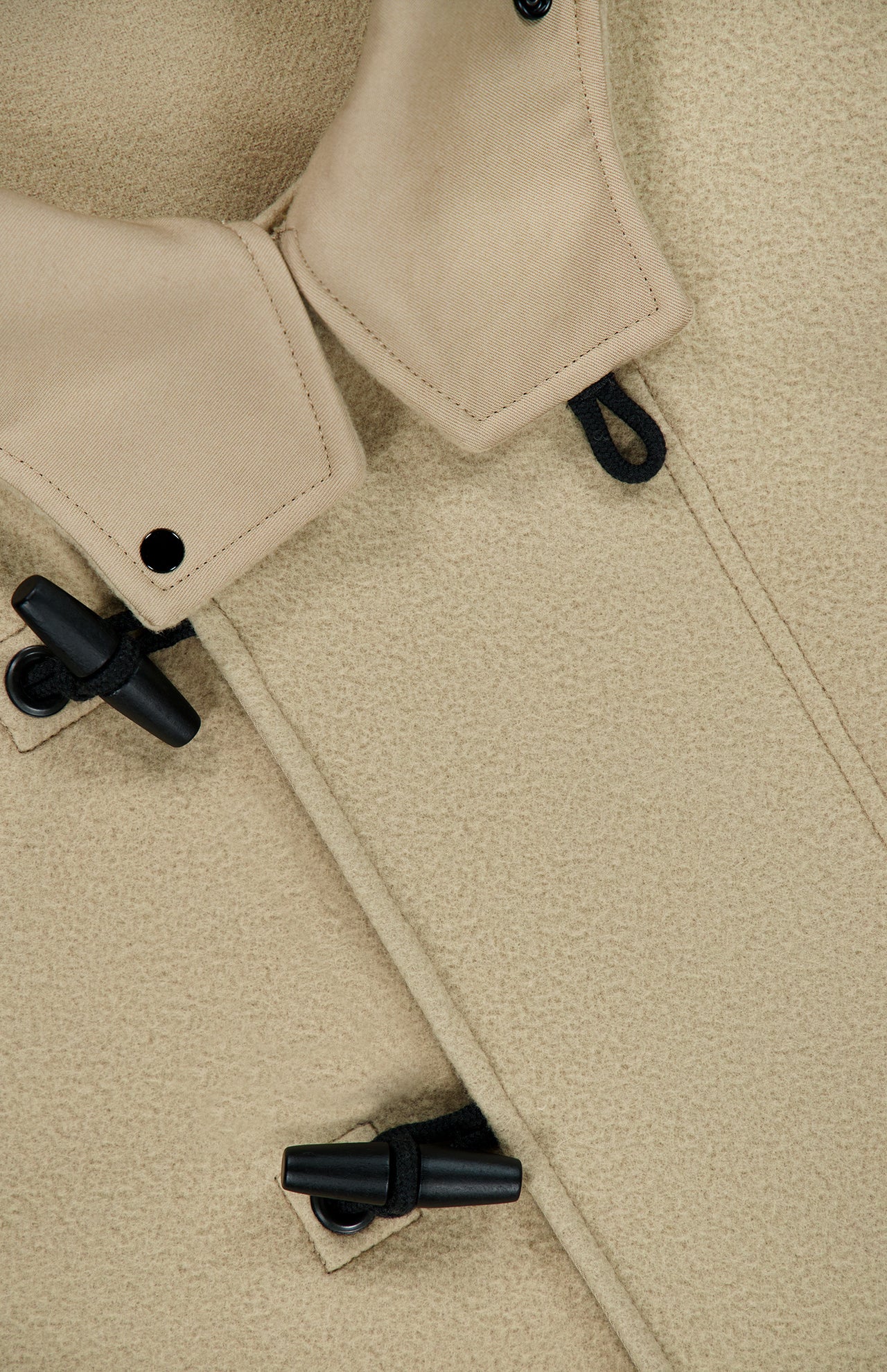 Close-up of the STONE ISLAND Hooded Toggle Jacket in beige, crafted from a textured wool-cashmere blend. The jacket features black toggle buttons threaded through black cord fastenings and is finished with a soft collar. The thick fabric gives it a warm, substantial feel.