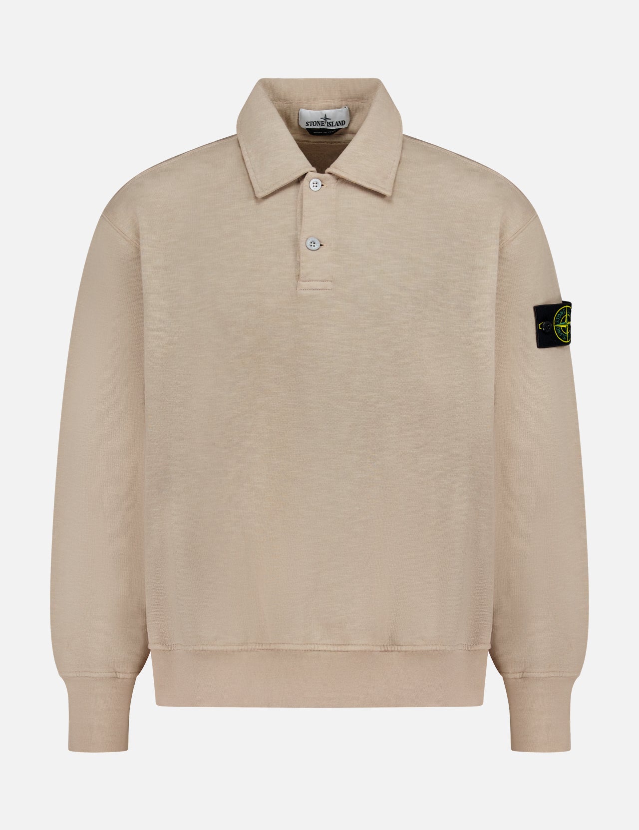 The Long Sleeve Polo Pullover Sweatshirt by STONE ISLAND features beige fabric, a collar with three buttons, and a black patch with yellow logo on the left sleeve, shown on a plain white background.