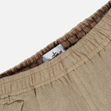 Close-up of the STONE ISLAND Loose-Fit Cargo Jogger Pant in beige, featuring an elastic waistband with visible stitching. A white tag with black text and the brand’s logo is sewn inside the waistband. The fabric has a soft, smooth texture reminiscent of premium wool sportswear.