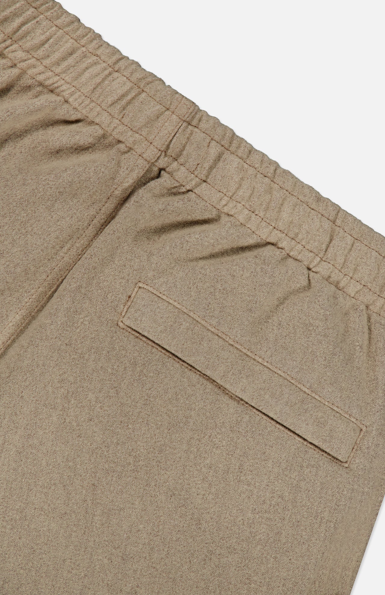Close-up of the STONE ISLAND Loose-Fit Cargo Jogger Pant in beige, featuring an elastic waistband and a single welt back pocket, shown against a white background.