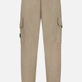 The STONE ISLAND Loose-Fit Cargo Jogger Pant features a beige colorway with an elastic waistband and cuffs, echoing the brand’s signature relaxed silhouette. Two side cargo pockets with flaps and a single back pocket add to its wool sportswear aesthetic. Displayed against a plain white background, the image highlights the back view of the pants.