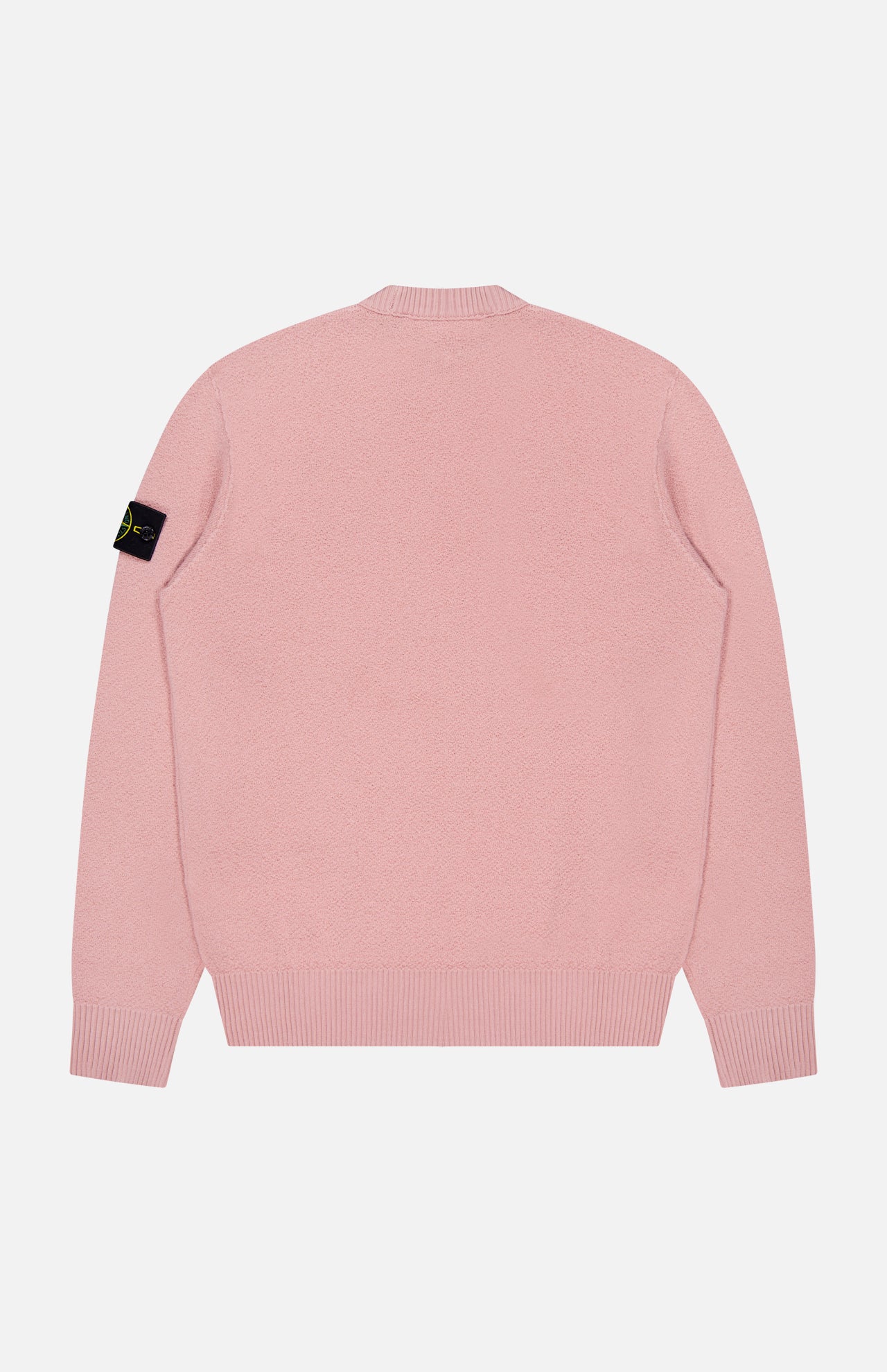 The Maglia Crewneck Sweater by STONE ISLAND is shown from the back in light pink, featuring ribbed cuffs and hem, plus a black logo patch on the left sleeve—blending modern street style with comfort.