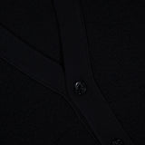 Close-up of a black textured fabric with two black buttons and a ribbed trim, likely part of the STONE ISLAND Maglia RWS Cardigan crafted from soft virgin wool.