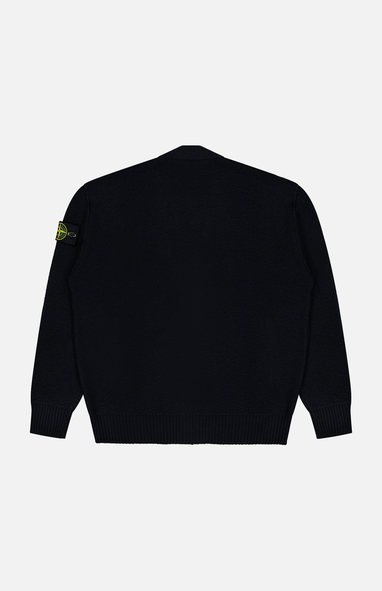 The Maglia RWS Cardigan by STONE ISLAND, crafted from luxurious virgin wool in black, is shown from the back against a plain white background. It features ribbed cuffs and hem and is distinguished by the iconic yellow and green STONE ISLAND patch on the left sleeve.