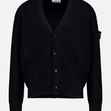 The Maglia RWS Cardigan by STONE ISLAND is a black knit cardigan featuring a V-neckline, ribbed cuffs and hem, two front pockets, and the distinctive Stone Island logo patch on the left sleeve. Crafted from soft virgin wool, it is presented against a plain white background.