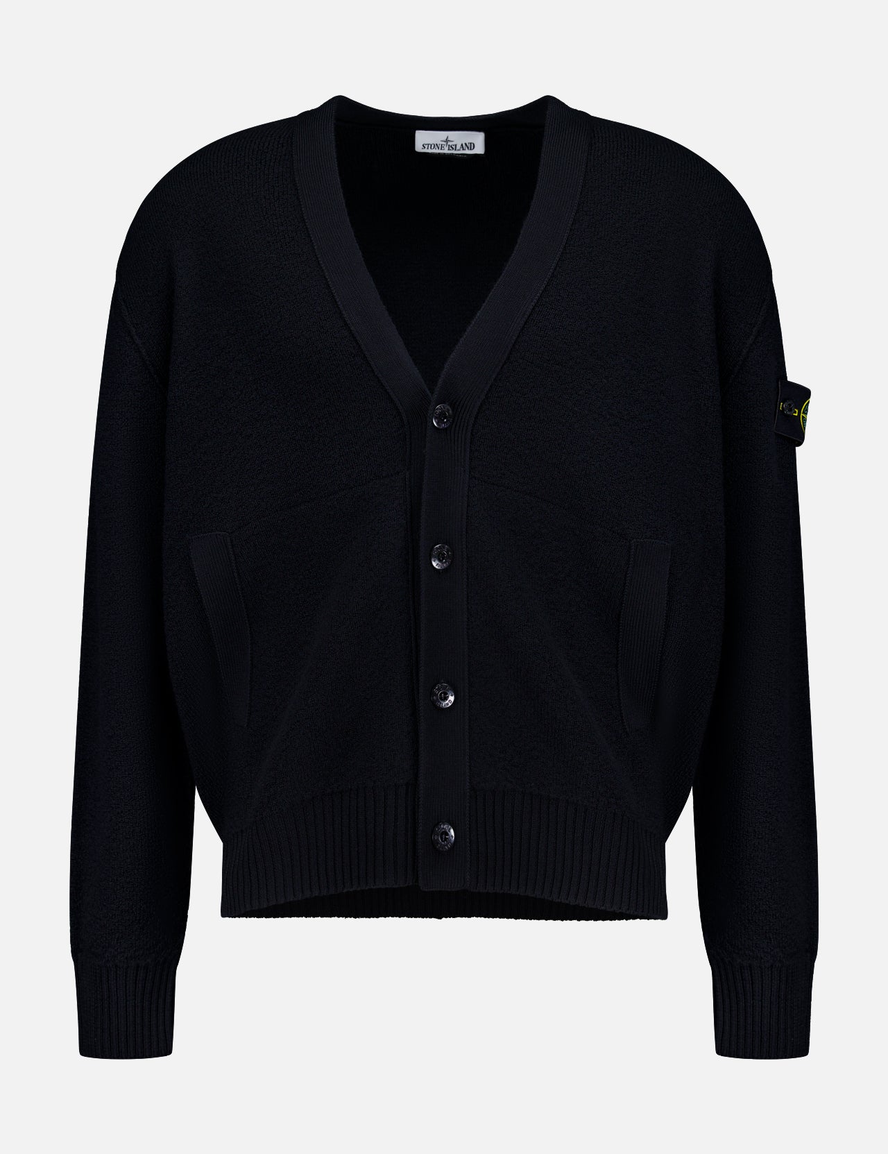 The Maglia RWS Cardigan by STONE ISLAND is a black knit cardigan featuring a V-neckline, ribbed cuffs and hem, two front pockets, and the distinctive Stone Island logo patch on the left sleeve. Crafted from soft virgin wool, it is presented against a plain white background.