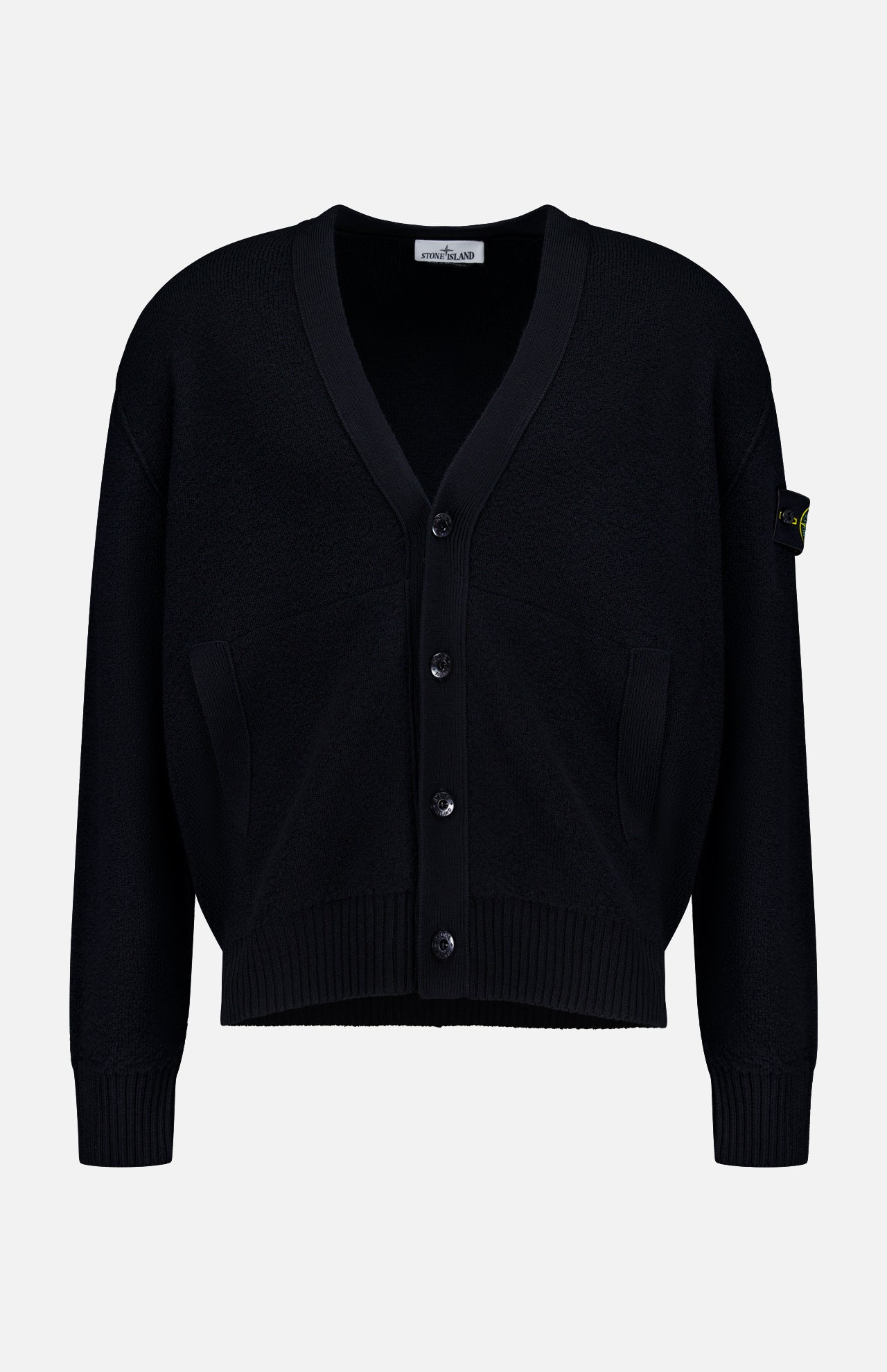 The Maglia RWS Cardigan by STONE ISLAND is a black knit cardigan featuring a V-neckline, ribbed cuffs and hem, two front pockets, and the distinctive Stone Island logo patch on the left sleeve. Crafted from soft virgin wool, it is presented against a plain white background.