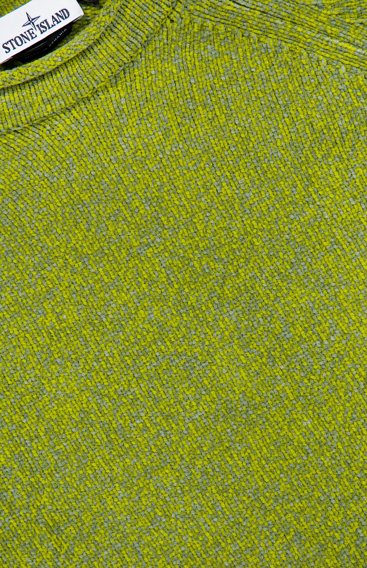 Close-up of the STONE ISLAND Maglia Speck Crewneck Sweater, featuring textured knit fabric interwoven with green and yellow threads and a visible brand label near the collar—a testament to the brand’s innovative sportswear design.