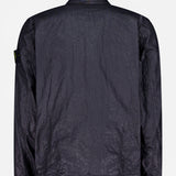 A dark, crinkled STONE ISLAND Crinkled Pocket Overshirt is shown from the back with a classic collar, long sleeves, and the signature black and yellow patch on the upper left arm against a plain white background.