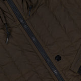 Close-up of the STONE ISLAND Quilted Hooded Jacket in brown, crafted from stretch nylon with a black zipper, a buttoned pocket, and visible quilting and stitching details inspired by the brand’s signature design elements.