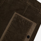 Close-up of dark olive green corduroy fabric with a textured vertical rib pattern and large rectangular pocket with button closure—signature elements of STONE ISLAND Regular-Fit Corduroy Trouser Pants.