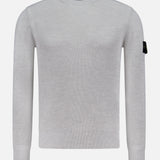 The STONE ISLAND Ribbed Crewneck Sweater in light grey features long sleeves, a ribbed knit design, and a black patch with the circular logo on the upper left sleeve. Shown on a plain white background.
