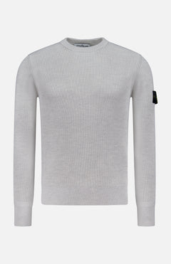The STONE ISLAND Ribbed Crewneck Sweater in light grey features long sleeves, a ribbed knit design, and a black patch with the circular logo on the upper left sleeve. Shown on a plain white background.