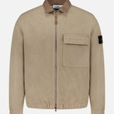 Stand Collar Zip Up Jacket by STONE ISLAND in beige, featuring a brown collar, large flap chest pocket, and black logo patch on the left sleeve, displayed against a plain white background—an iconic blend of streetwear and sportswear style.