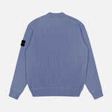 The STONE ISLAND Ribbed Knit Crewneck Sweater in light blue cotton features ribbed cuffs and hem, a back view, and the signature black patch with yellow logo on the left sleeve—perfect for men's sportswear collections.