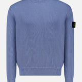 The STONE ISLAND Ribbed Knit Crewneck Sweater in light blue cotton features a ribbed design, crew neck, and signature black patch with yellow emblem on the upper left sleeve—ideal for men’s sportswear collections.