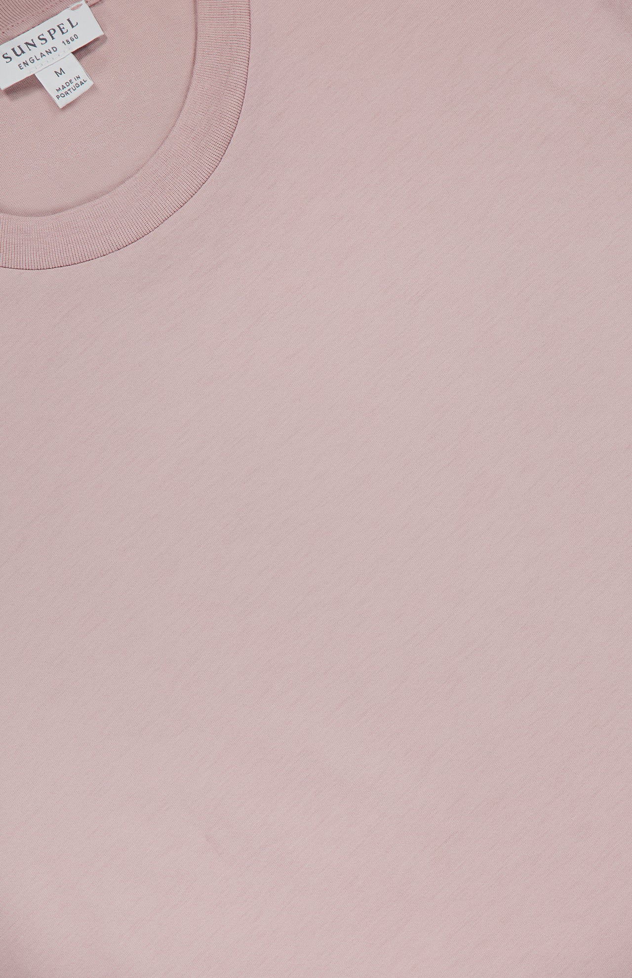 A close-up of the SUNSPEL Classic Short Sleeve T-Shirt in pale pink, showcasing its soft 100% cotton fabric, round collar, and visible brand label inside the neckline.