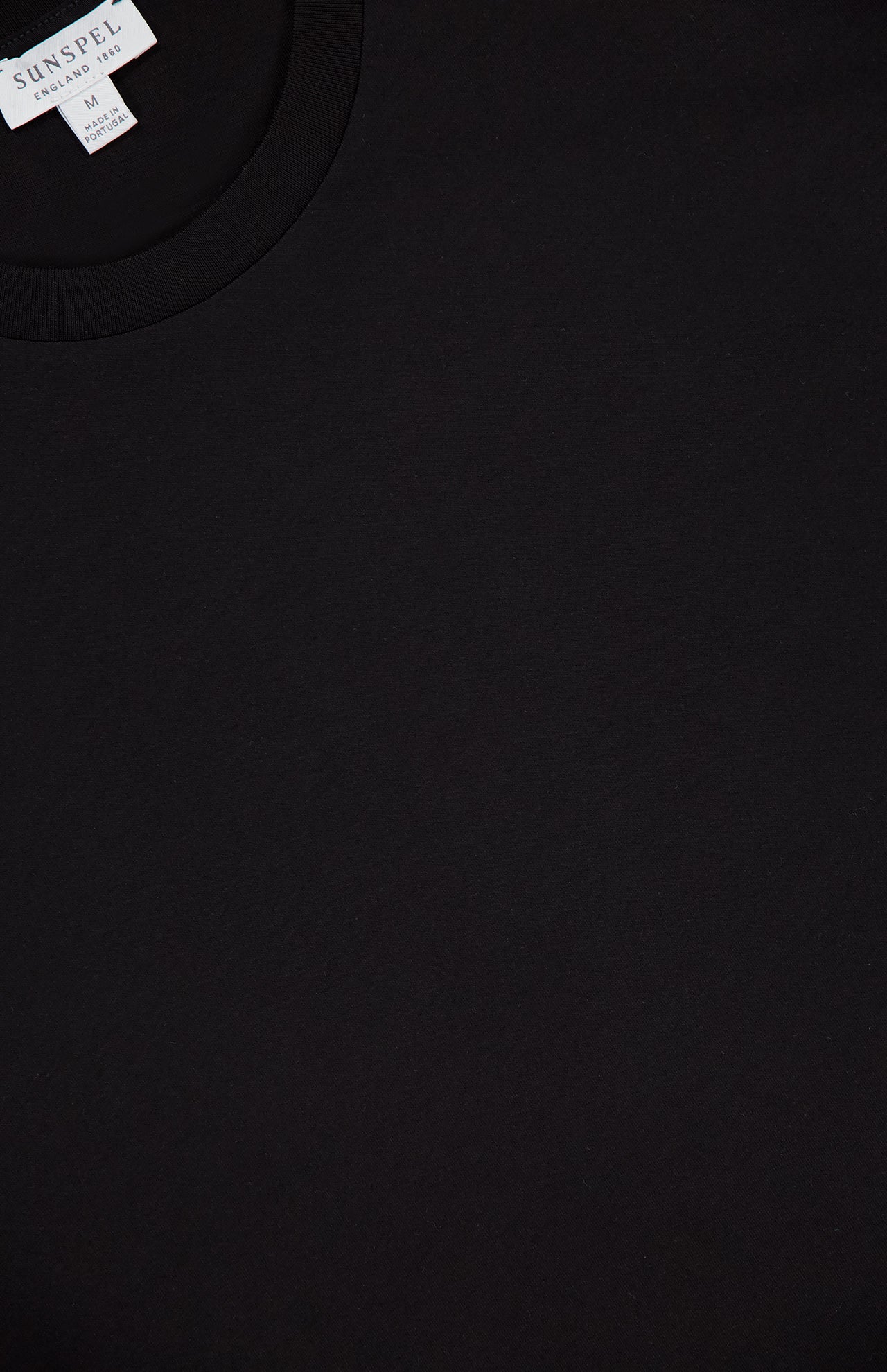 A close-up of the SUNSPEL Short Sleeve Classic T-Shirt in plain black cotton, highlighting the crew neckline and upper chest, with a "Made in Portugal" label partly visible at the top.
