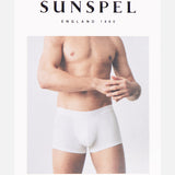 A shirtless man in white Superfine Trunk boxer briefs stands against a light background with SUNSPEL above and STRETCH COTTON below, highlighting men's underwear crafted from superfine cotton jersey on the packaging.